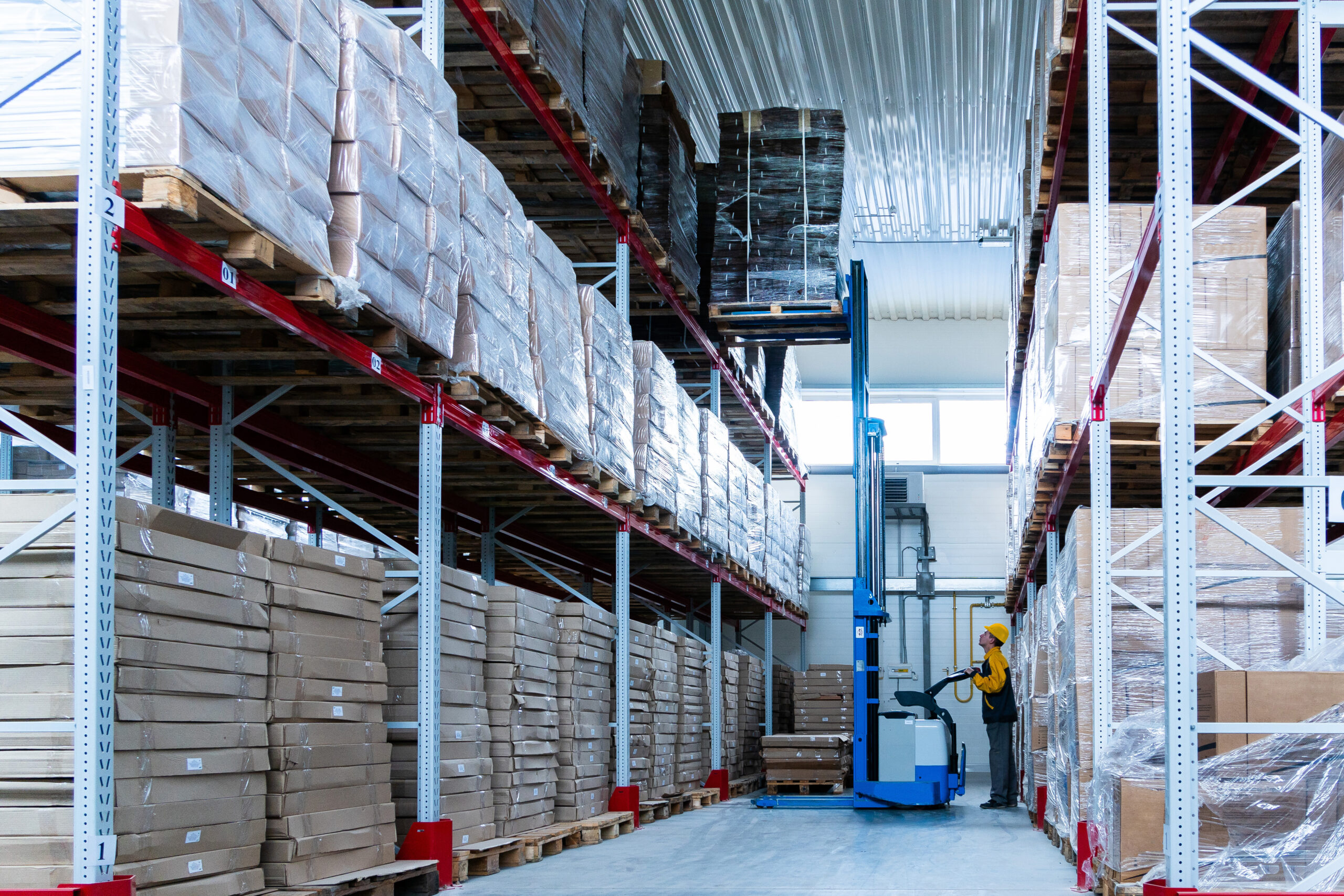 warehouse worker driver in uniform delivery and loading cardboxes by forklift stacker loader.