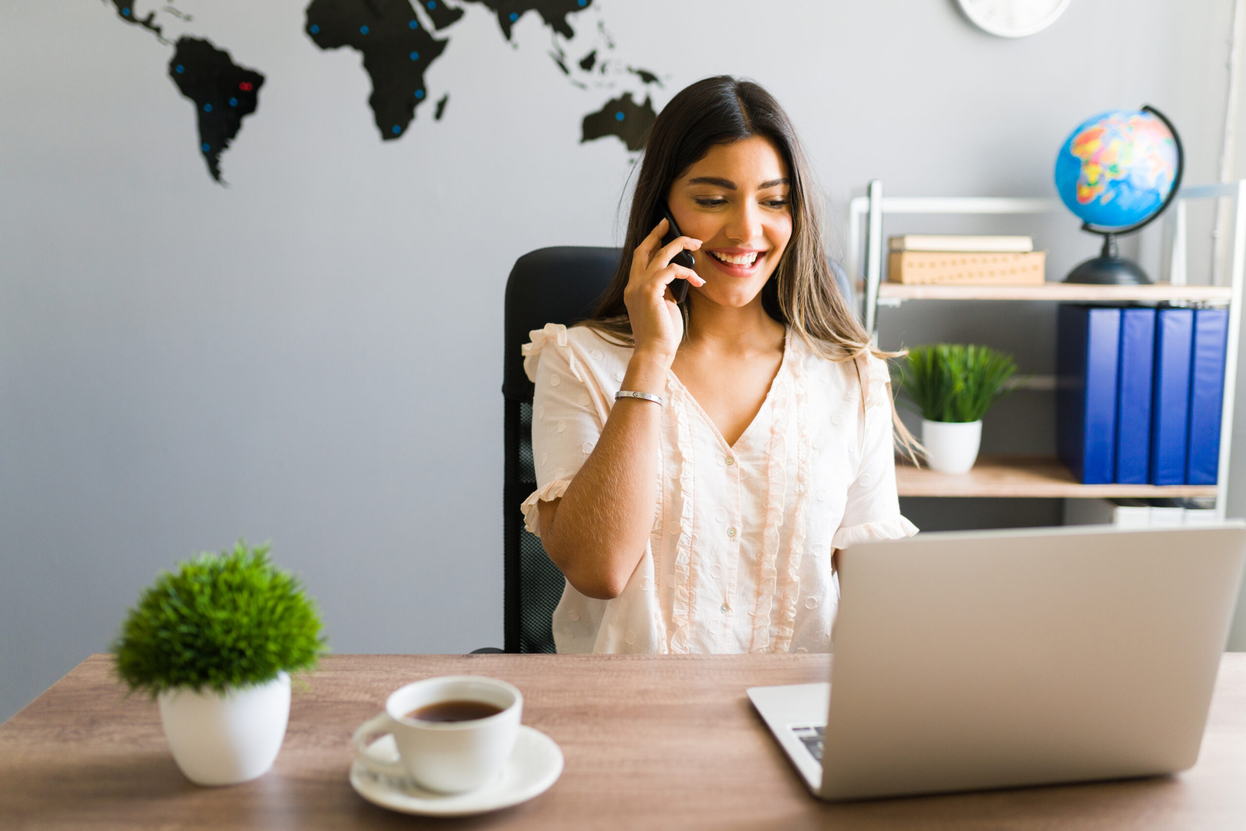 I can help you book your flight. Beautiful sales representative at a travel agency taking a call from a client and giving information about a package tour vacation
